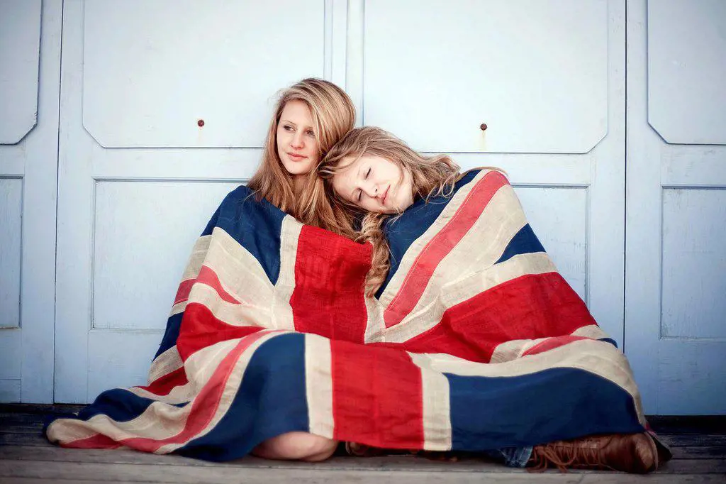 Girls covered in British flag sitting against wall