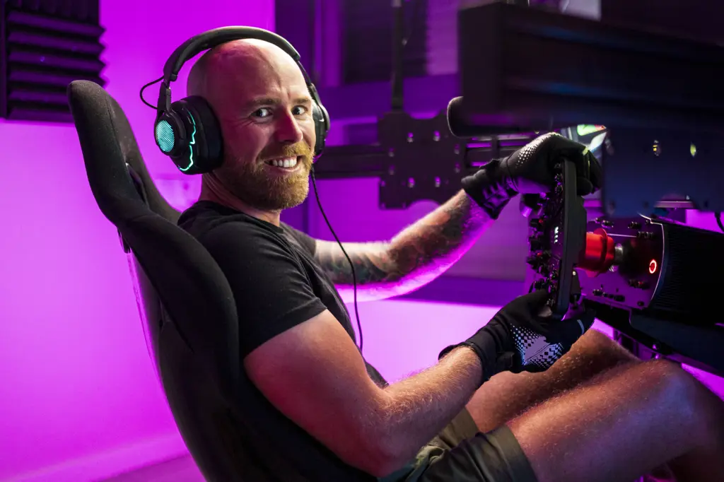 Smiling bald male gamer wearing headphones playing game at studio