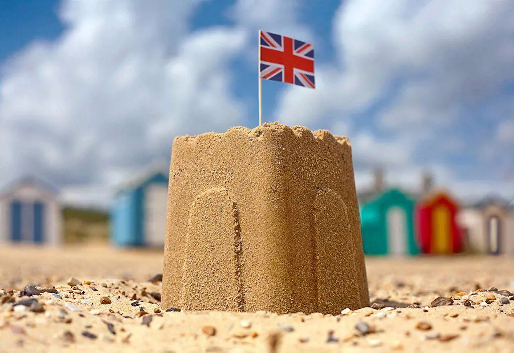 Sandcastle with Union Jack flag on beach during sunny day