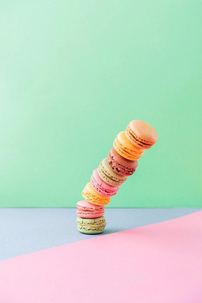 Studio shot of stack of pastel colored macaroon cookies falling down