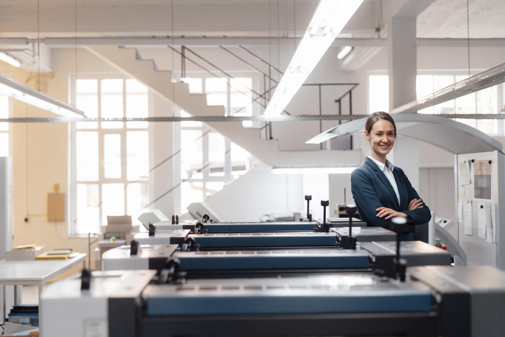 Smiling female business professional standing with arms crossed in industry