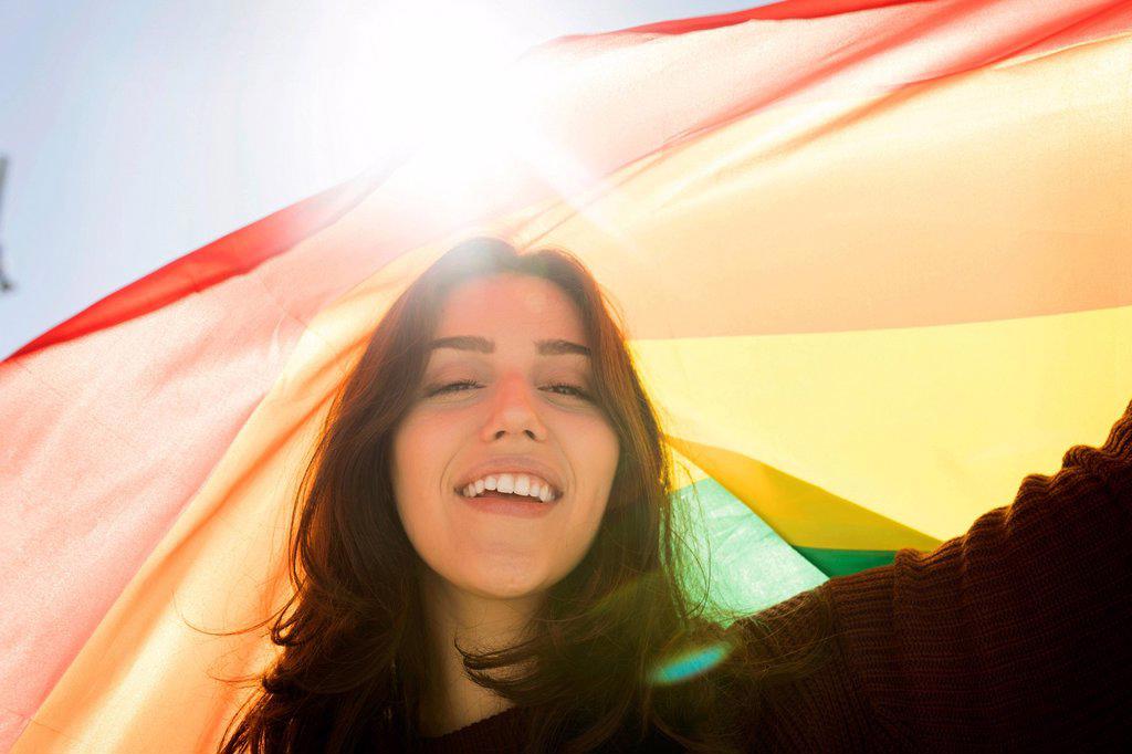 Young woman with rainbow flag during sunny day