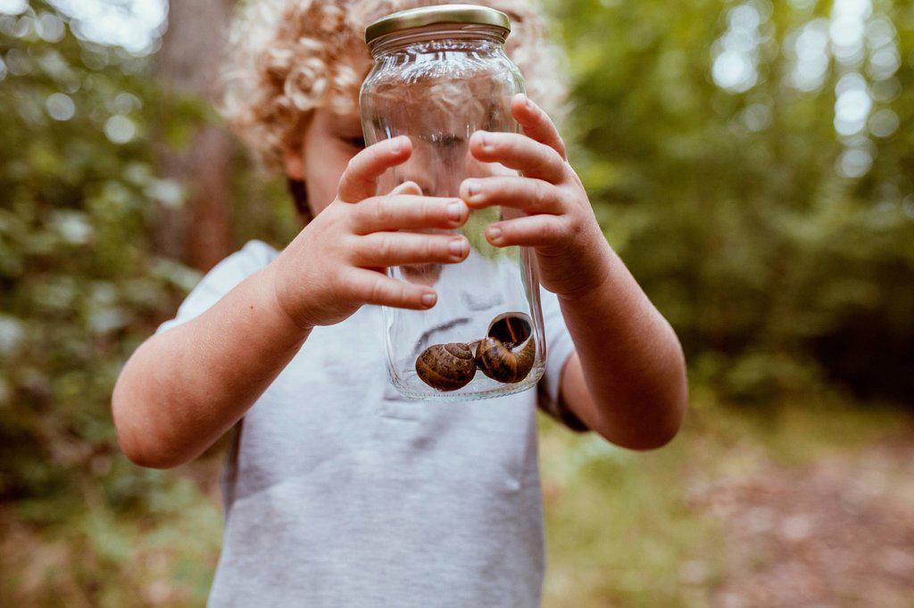 Boy holding glass jar with snails