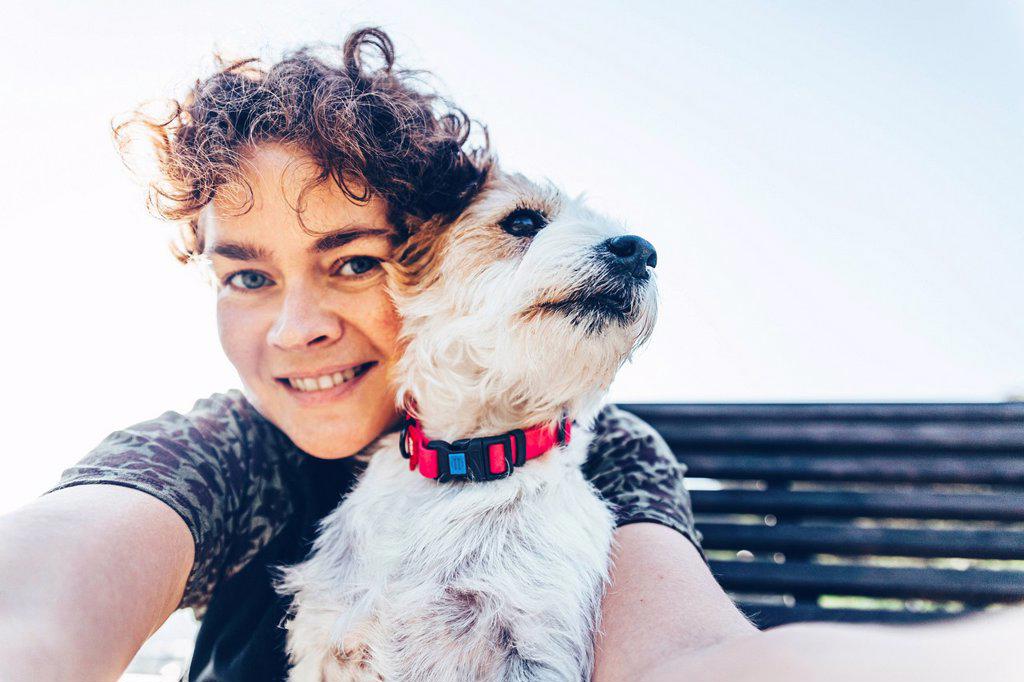 Smiling woman with Jack Russell Terrier taking selfie during sunny day