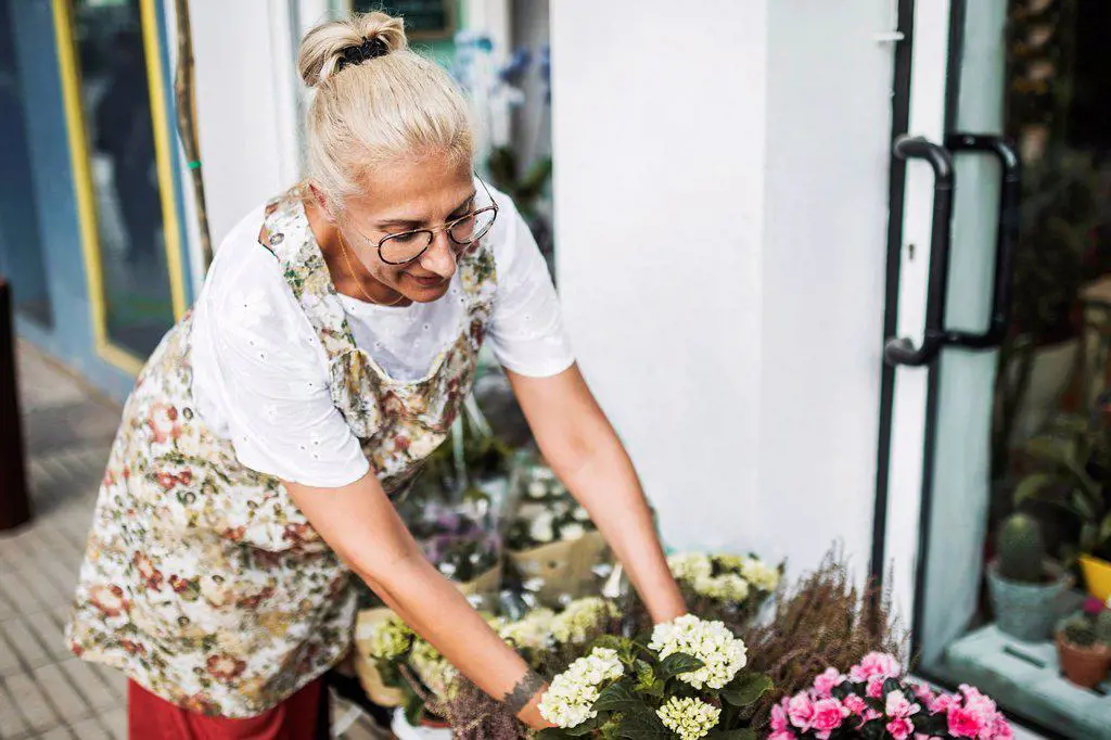 Blond female florist arranging flowers outside store
