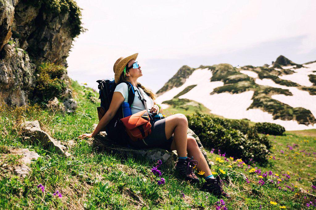Female hiker with backpack relaxing on mountain
