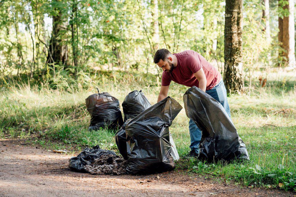 Mid adult activist with garbage bags in forest