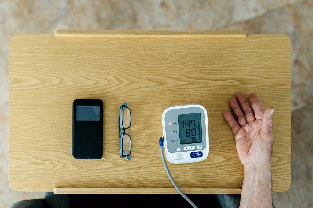 Man checking blood pressure on table at home