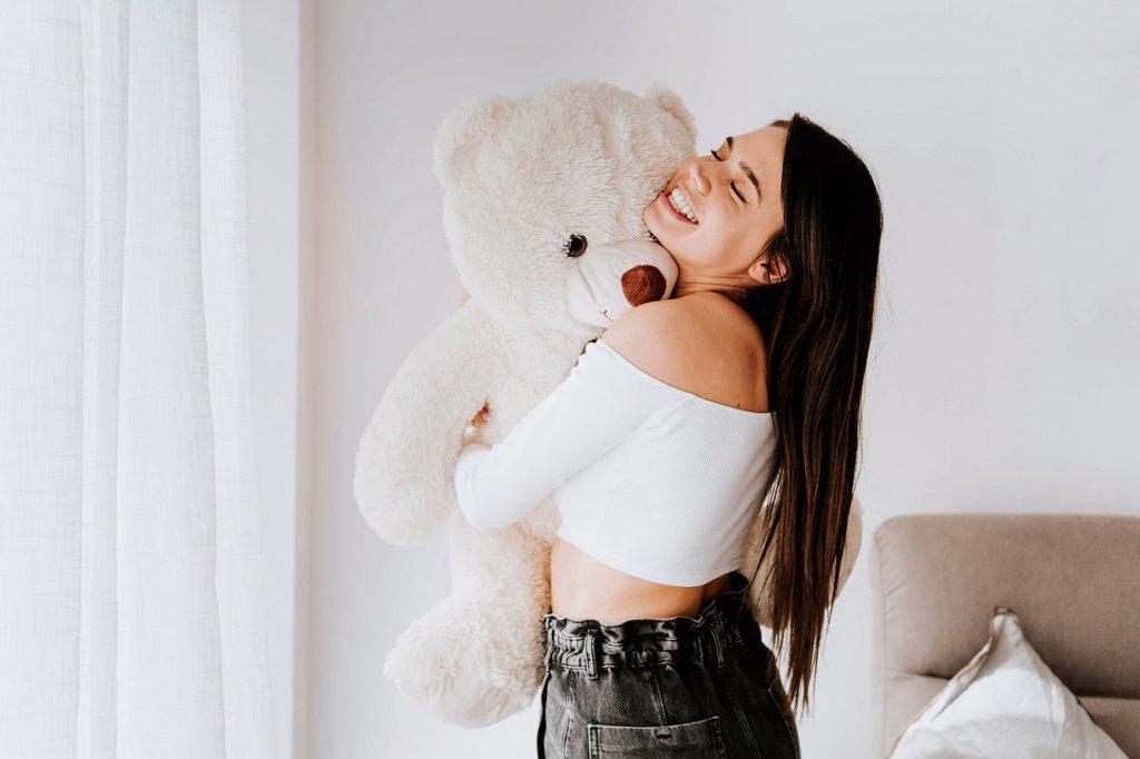 Young woman hugging teddy bear at home