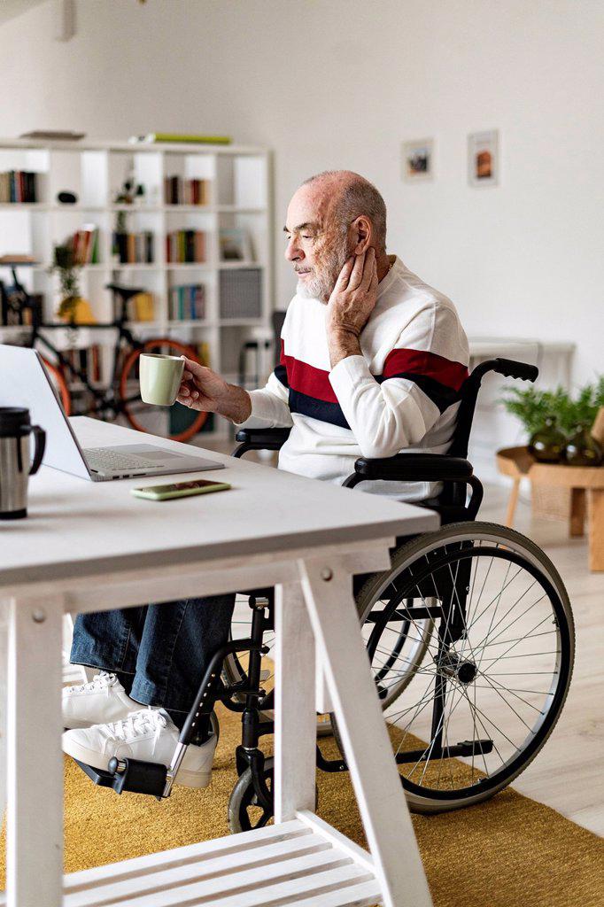 Senior businessman with physical disability looking at laptop on desk