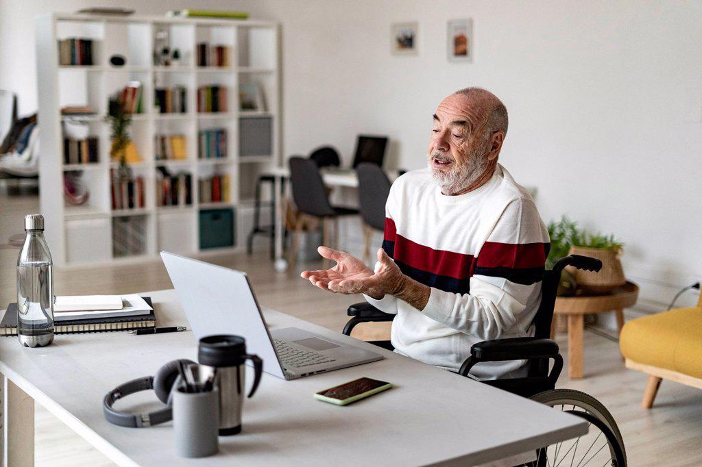 Senior businessman talking to video call through laptop on table