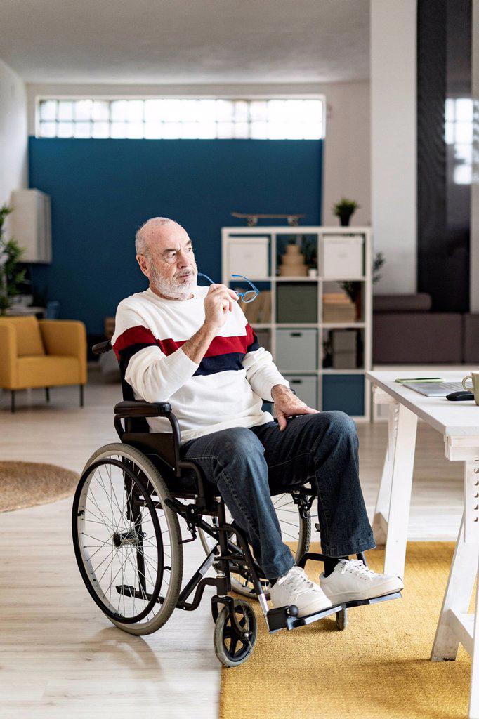 Thoughtful businessman sitting on wheelchair at home office