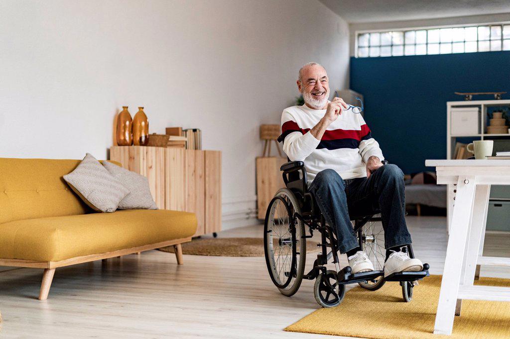 Smiling senior freelancer on wheelchair in living room