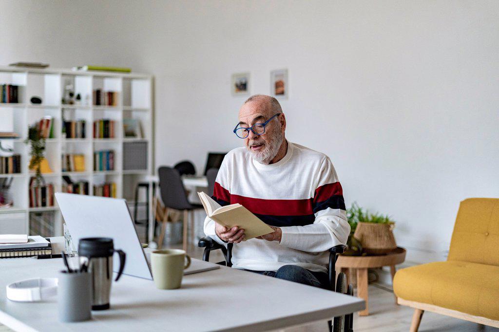 Senior disabled man reading diary at home office