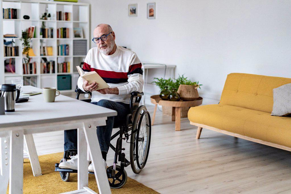 Serious disabled man holding diary at home office