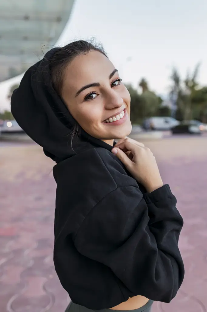 Smiling sportswoman wearing hoodie in park