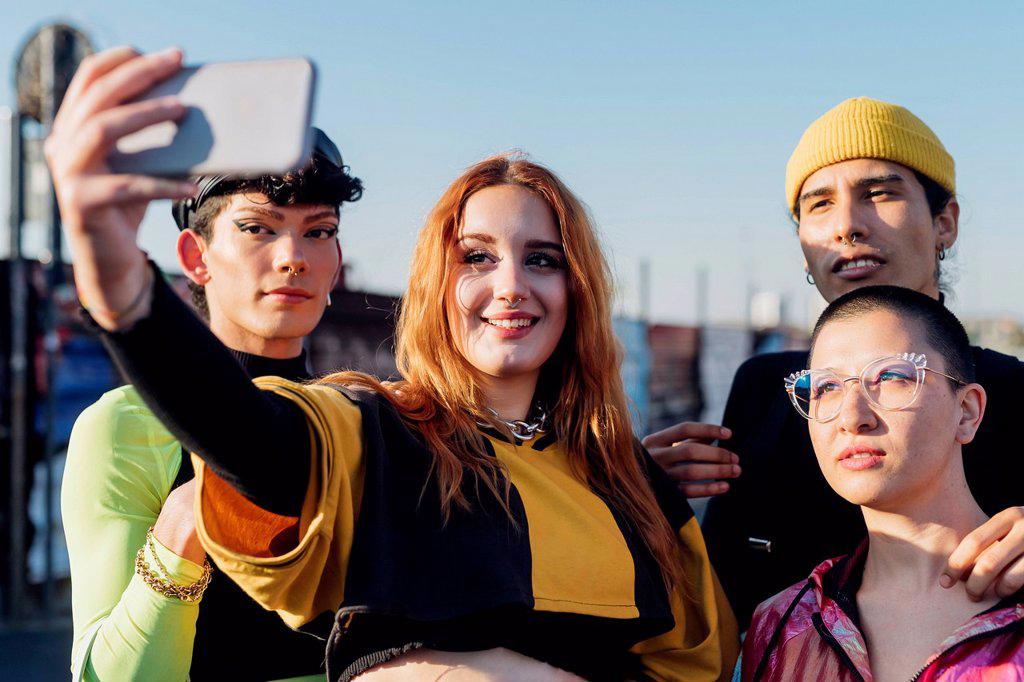 Redhead woman taking selfie with friends through smart phone on sunny day