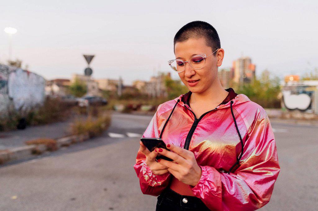 Woman with pink jacket using mobile phone on road