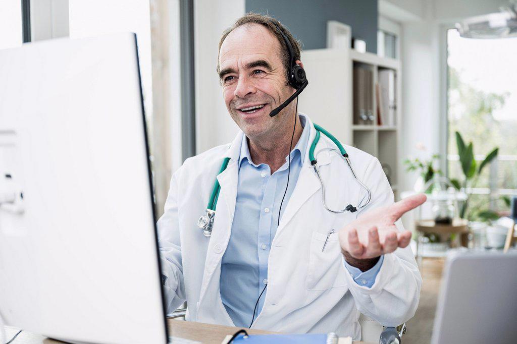 Smiling doctor gesturing on video call at clinic