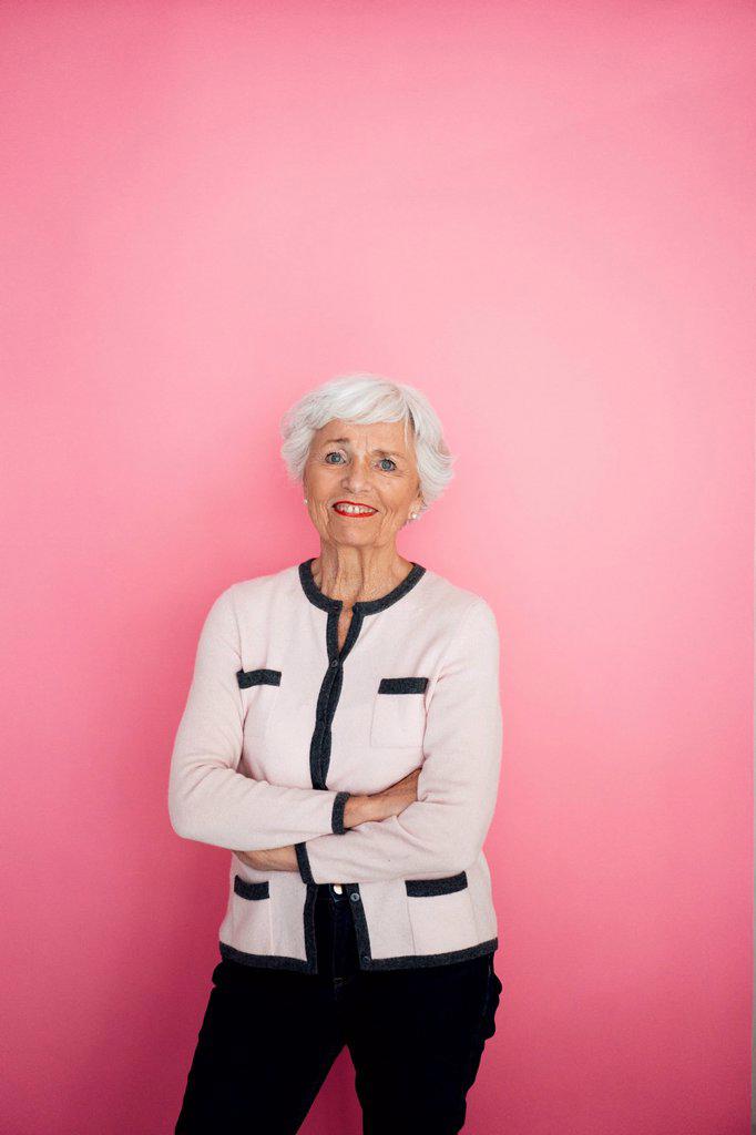 Woman with arms crossed again pink background