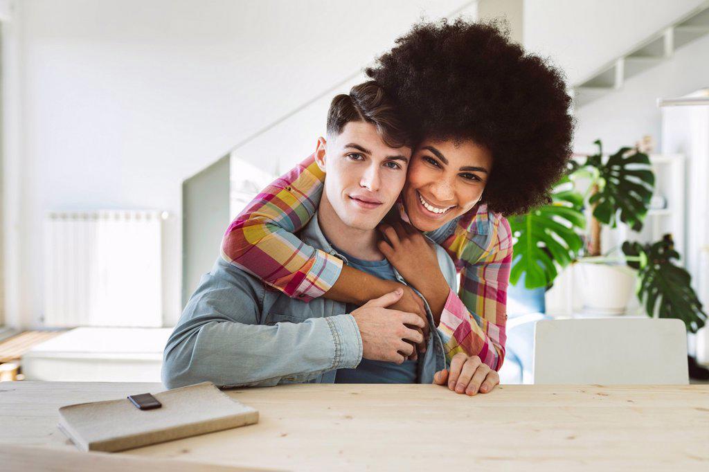 Happy woman embracing young man from behind at home