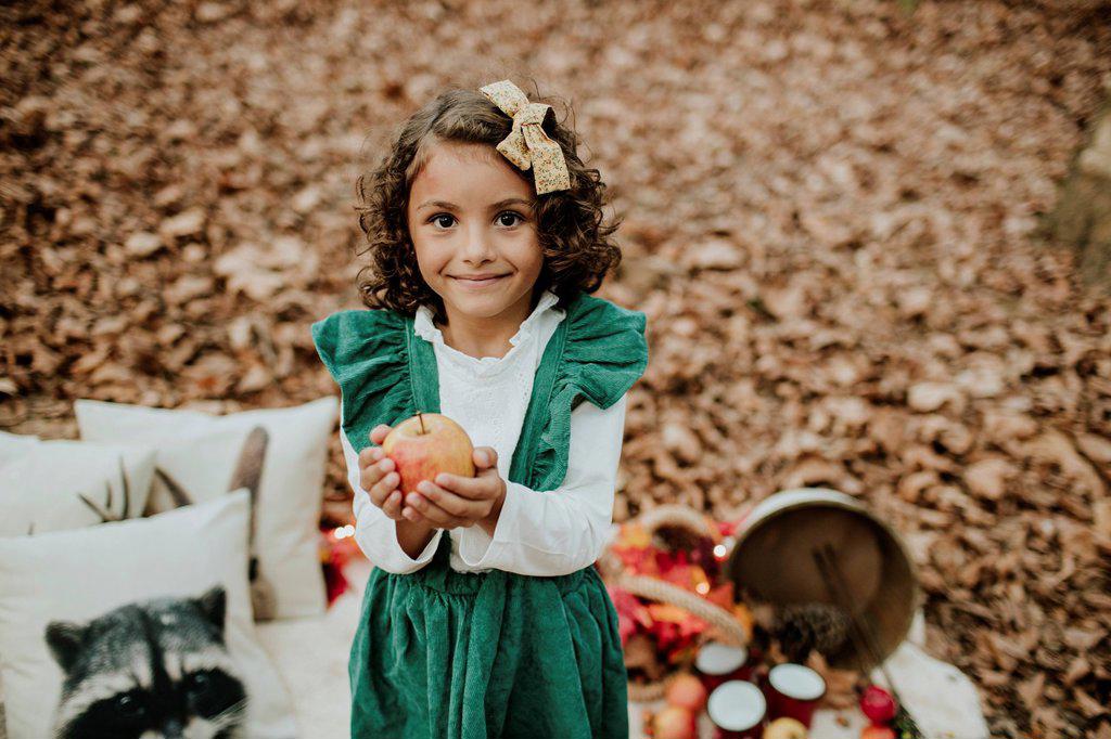Smiling girl holding apple at forest in Christmas