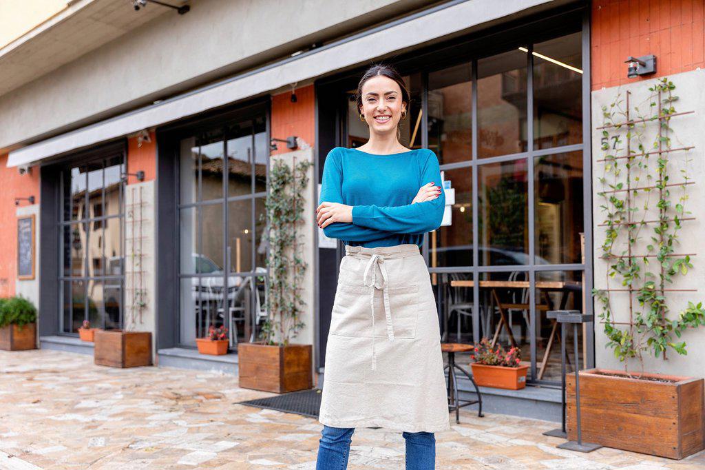 Smiling entrepreneur with arms crossed outside coffee shop