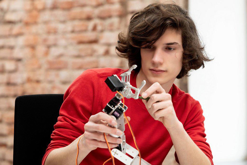 Teenage boy working on small robotic arm