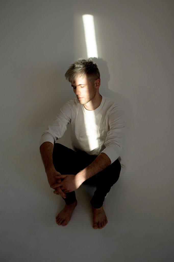 Stressed young man with beam of light on face