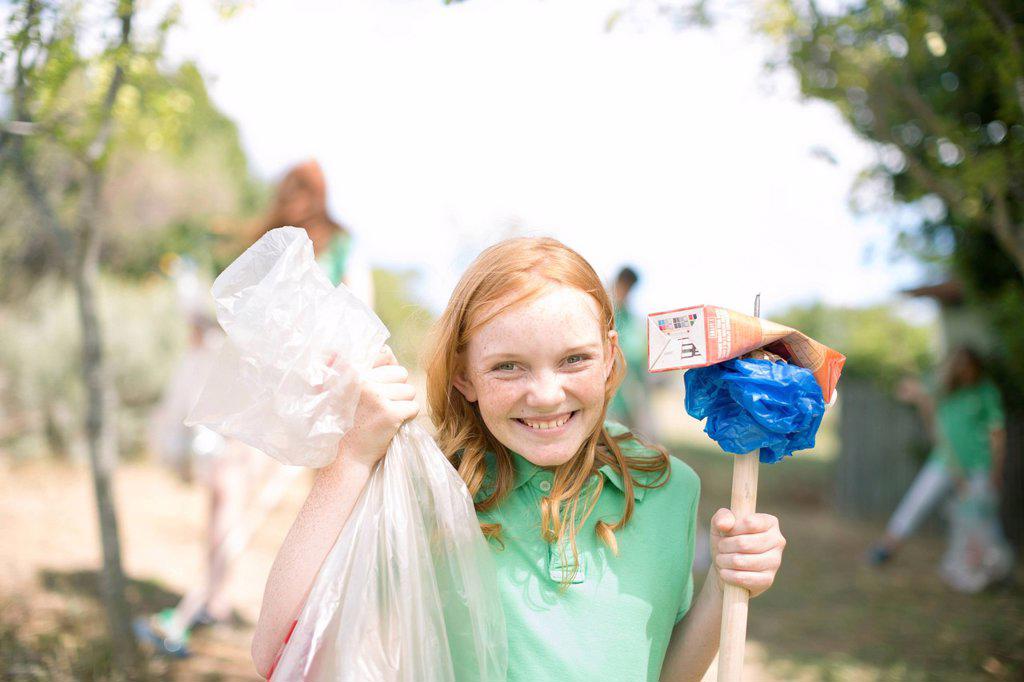 Portrait of smiling girl showing picked up garbage