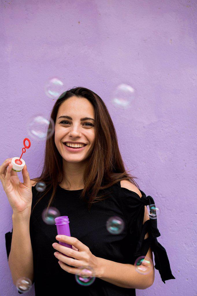 Portrait of smiling young woman with bubble ring