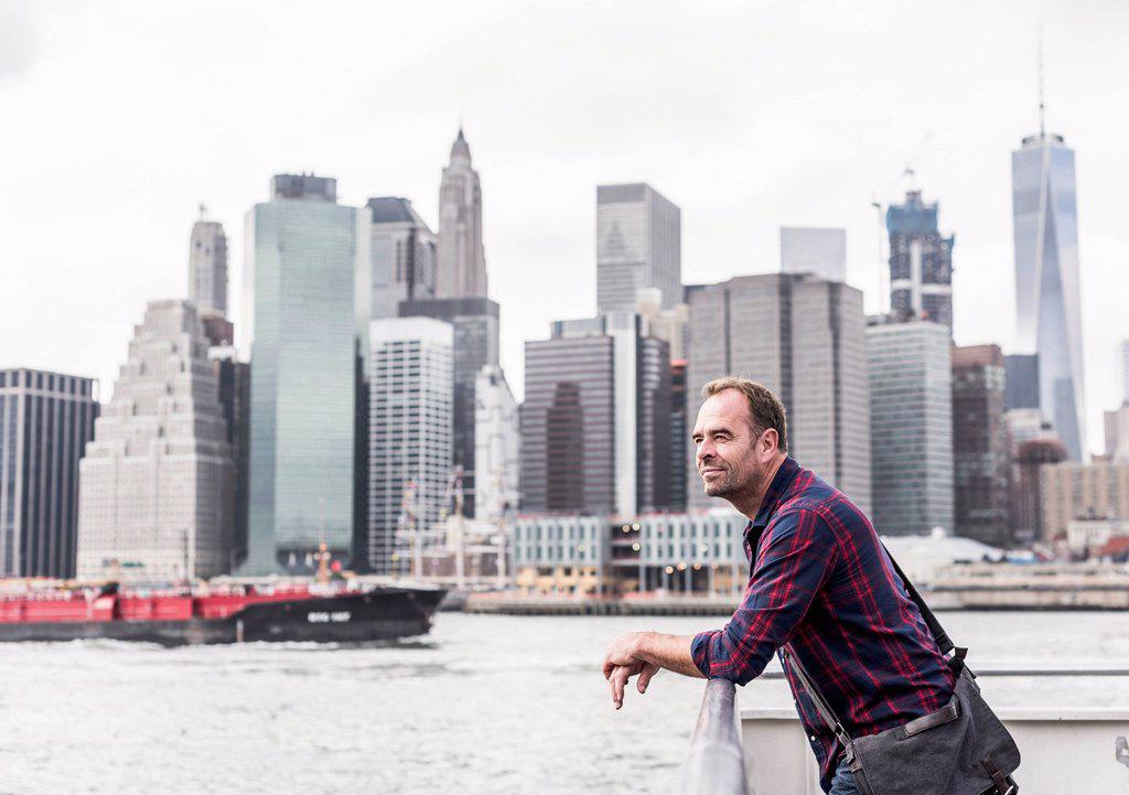 USA, New York City, man on ferry with Manhattan skyline in background