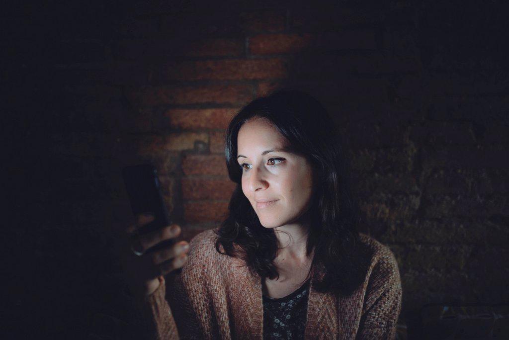 Portrait of woman using smartphone at home in the dark