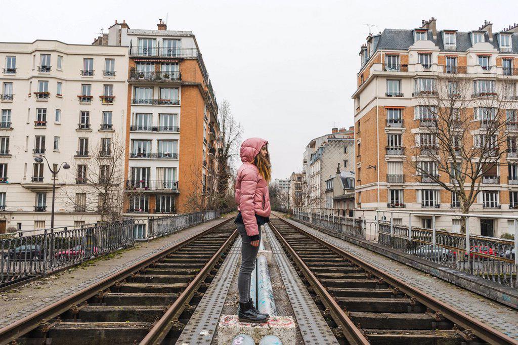 France, Paris, woman standing between abandoned railway tracks