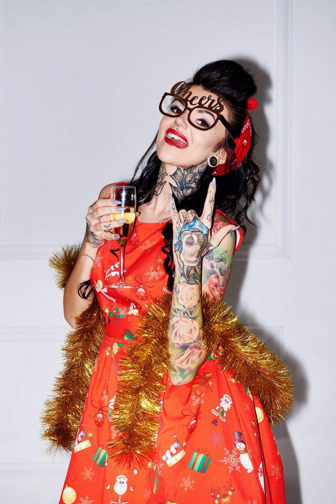 Portrait of tattooed woman with champagne glass showing Rock And Roll Sign