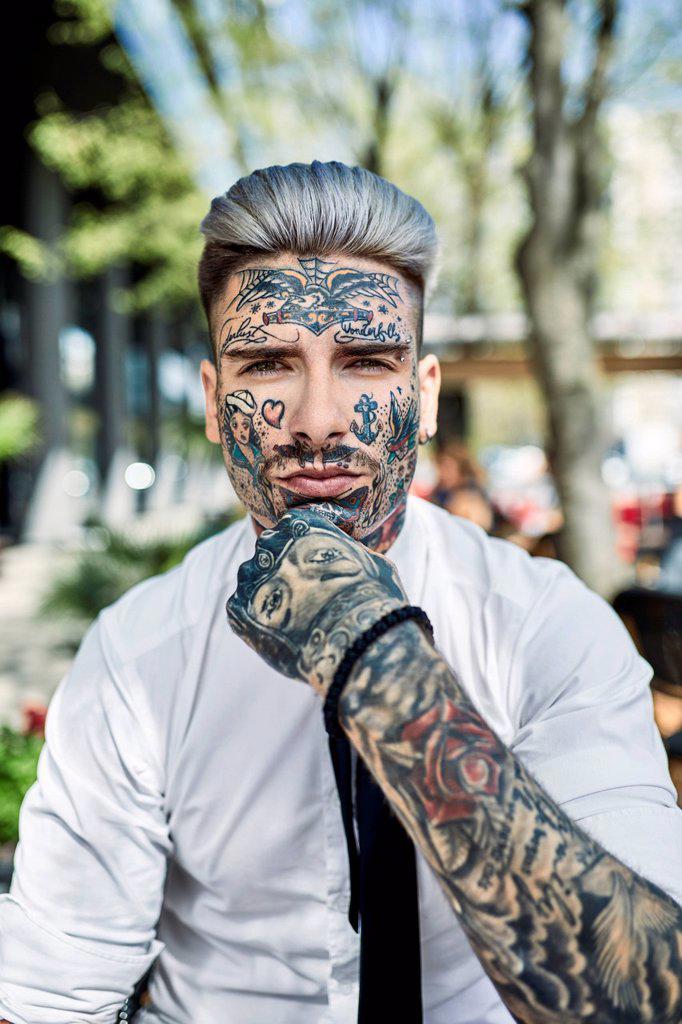 Young businessman with tattooed face, looking at camera