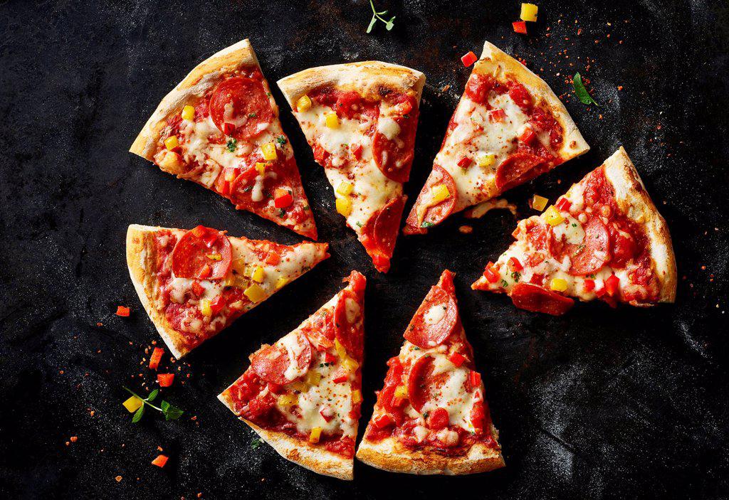 Sliced pizza with salami on dark ground
