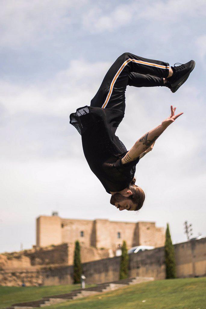 Spain, Lleida, tattooed man doing parkour in a park