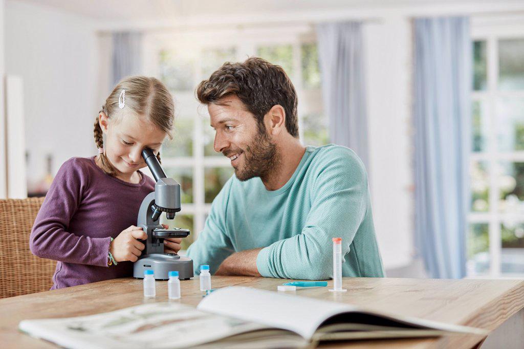 Father and daughter using microscope at home