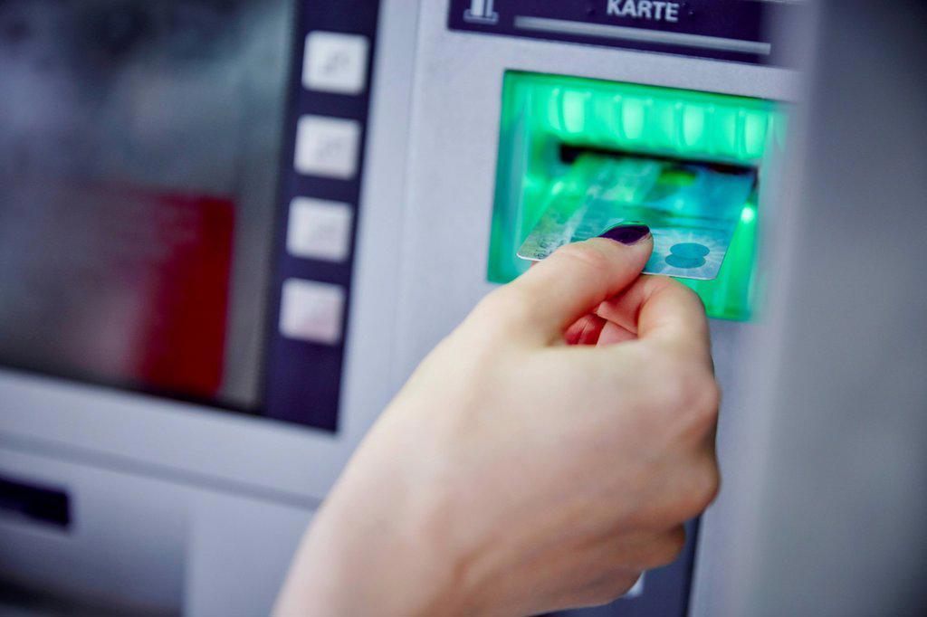 Close-up of woman putting card into slot of cash machine