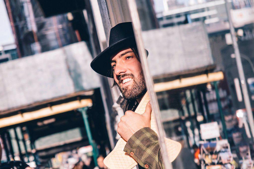 USA, New York City, portrait of bearded man with skateboard wearing black hat