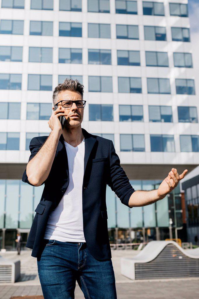 Angry businessman on cell phone walking outside office building