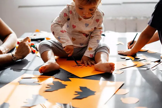 Baby girl painting halloween decoration at home