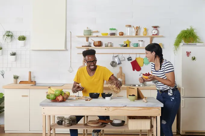 Multiethnic couple laughing, breakfasting together in the kitchen