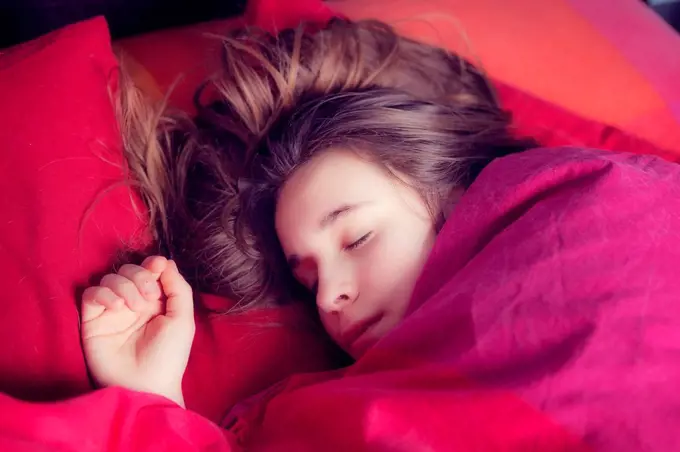 Portrait of girl sleeping in colourful bedding