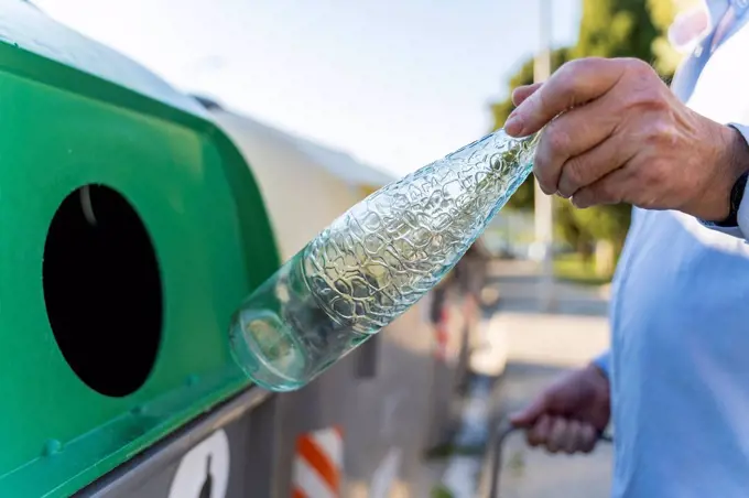 Close-up of man putting bottle into bottle bank