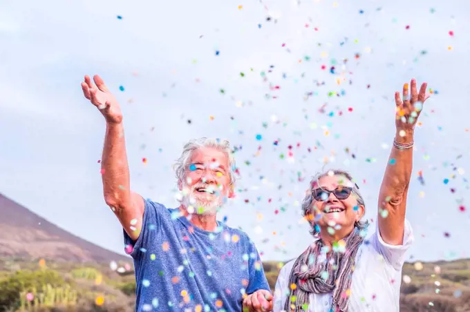 Happy senior couple celebrating with confetti outdoors