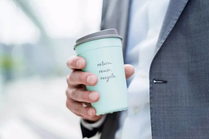 Close-up of businessman holding recycable takeaway coffee cup