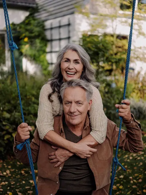 Happy woman embracing senior man on a swing in garden