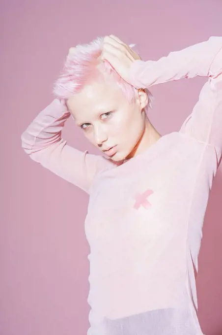Portrait of young woman with short pink hair wearing pink top in front of pink background